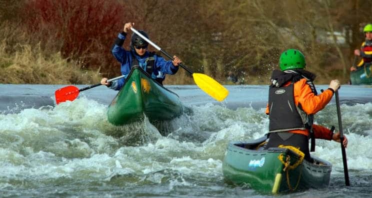 Advanced Canoe Leader. Tandem canoes head across advanced water as a leader looks on.