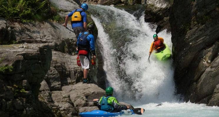 Advanced White Water Kayak leader. A kayak heads over a large falls whilst a leader looks on.