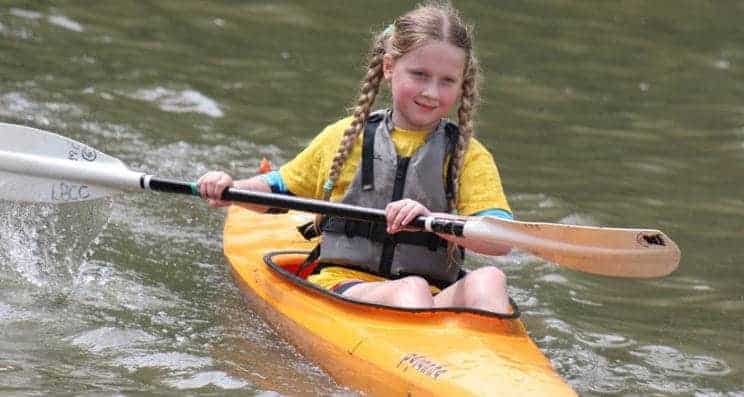 Coaching young paddlers. A young girl heads out in a kayak.