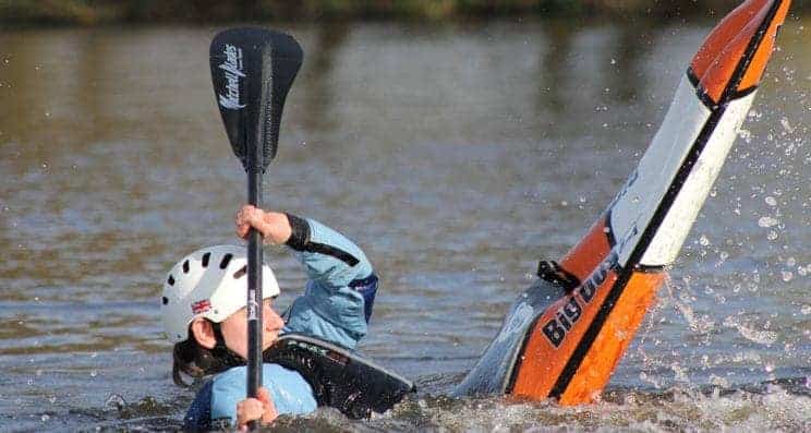 Fundamental Paddlesport Skills. A freestyle kayaker performs a move on the water.