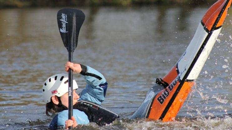 Fundamental Paddlesport Skills. A freestyle kayaker performs a move on the water.