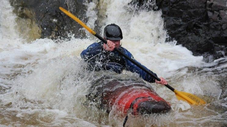 Optimising Fitness and Performance. A kayaker concentrates on the water ahead in rough water.