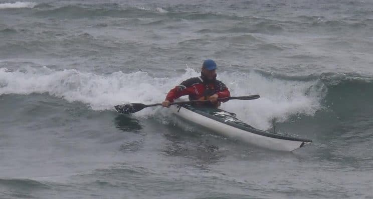 Sea Kayak Leader. A paddler navigating a moderate wave on the sea.