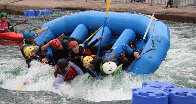 Stadium Raft Guide. A group in a stadium raft are being tipped out on the water.
