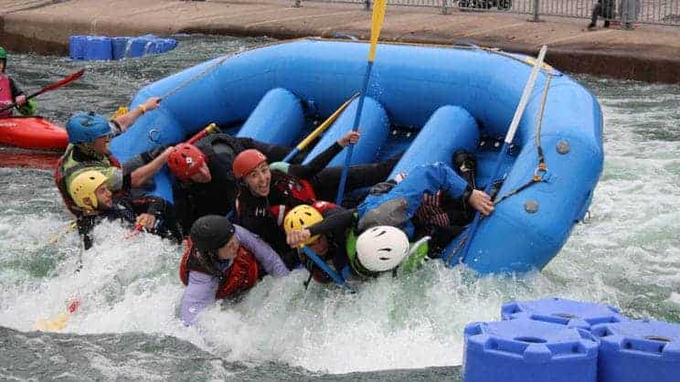 Stadium Raft Guide. A group in a stadium raft are being tipped out on the water.