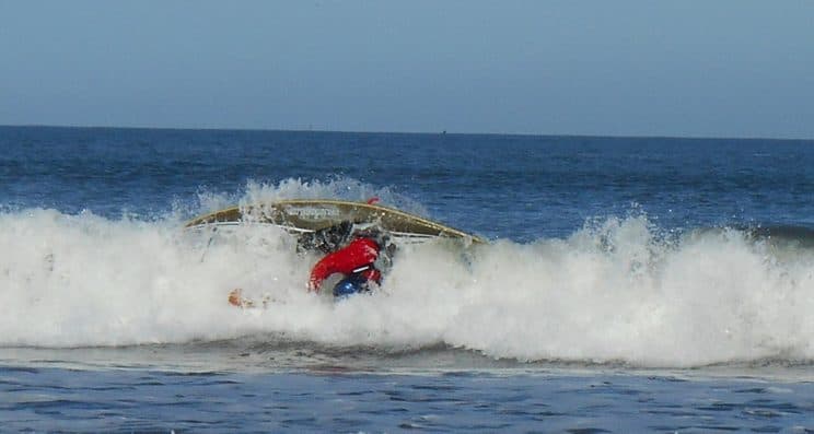 Advanced Surf Safety and Rescue. A surf kayaker being wiped out on a wave.