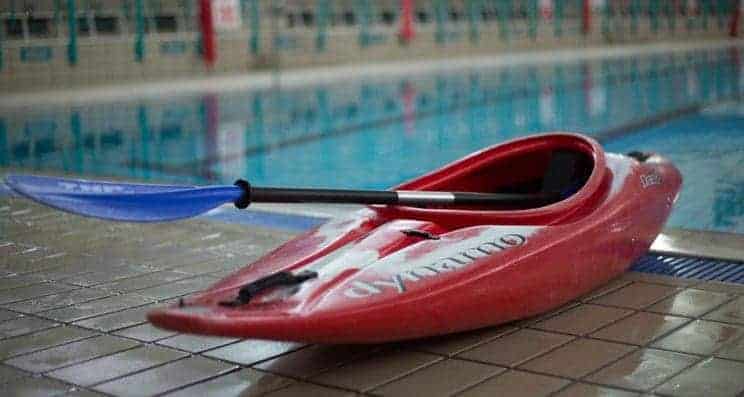 Swimming Pools. A kayak sits by a pool.