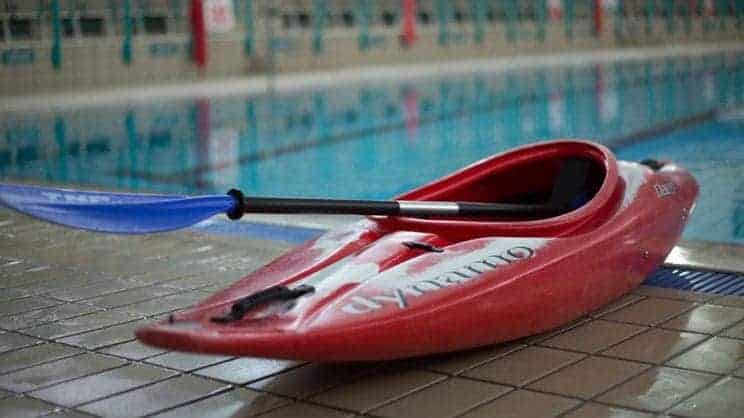 Swimming Pools. A kayak sits by a pool.