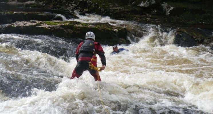 White Water Safety and Rescue. A paddler performing a rescue to another stuck in white water.