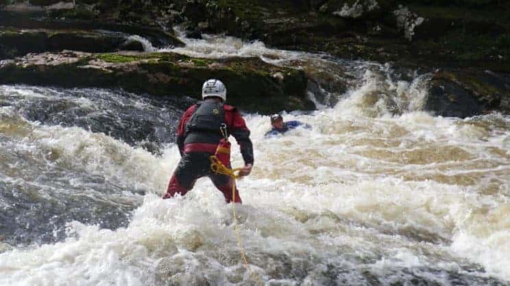 White Water Safety and Rescue. A paddler performing a rescue to another stuck in white water.