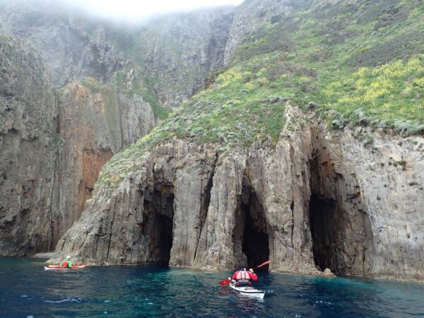 Paddler in kayak exploring some caves from the sea. Leading in Unfamiliar Environments eLearning