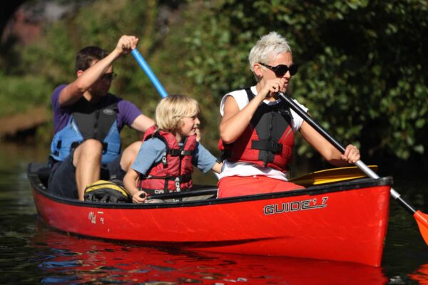 This image shows a family (a woman, child and a men) in a boat. British Canoeing Personal Provider Award Provider eLearning.